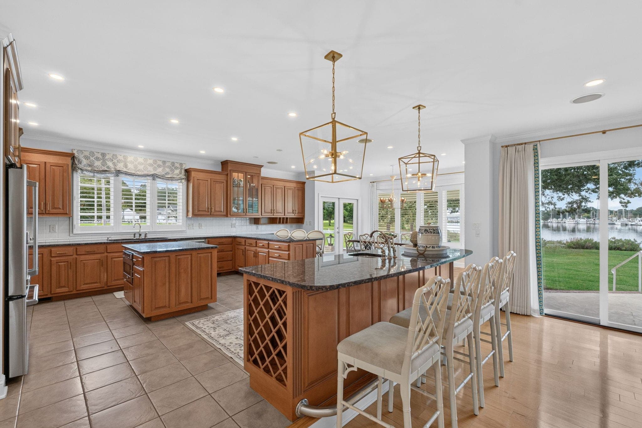 The chef's kitchen, an oversized granite island with peninsula seating under a pair of lantern pendants, sliders to the patio.