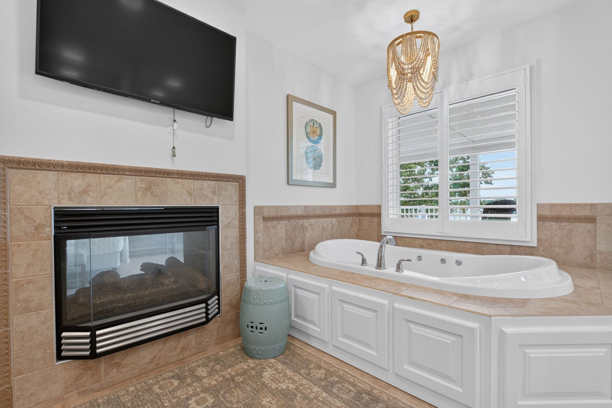 The primary bath: a jetted tub beside the fireplace, with a water view from the window.